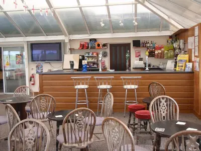 a restaurant with tables and chairs and a bar at Chalets & Lodges at Atlantic Bays Holiday Park in Padstow