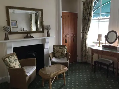 a living room with a fireplace and two chairs and a mirror at Dolphin Guest House in Looe