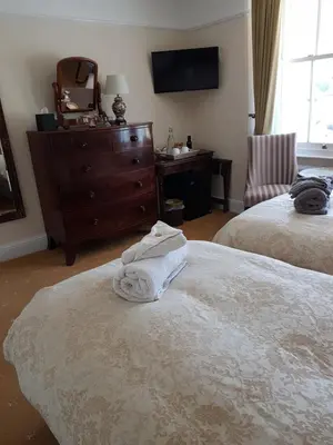 a bedroom with two beds and a dresser and a mirror at Dolphin Guest House in Looe
