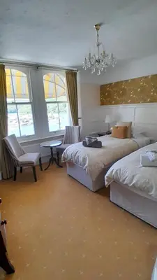 a bedroom with two beds and a chandelier at Dolphin Guest House in Looe
