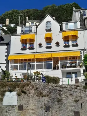 a white building with yellow umbrellas in front of it at Dolphin Guest House in Looe