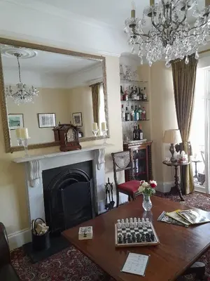 a living room with a table and a fireplace at Dolphin Guest House in Looe
