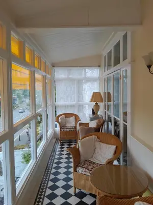 a living room with chairs and a table and windows at Dolphin Guest House in Looe