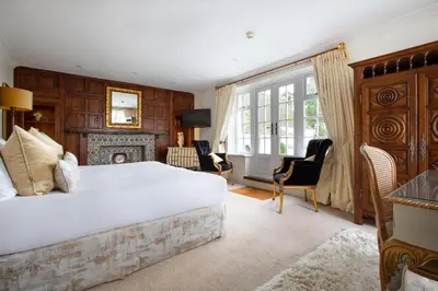 a bedroom with a large bed and a fireplace at Talland Bay Hotel, Looe in Talland