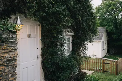 an ivy covered house with a white door at Talland Bay Hotel, Looe in Talland