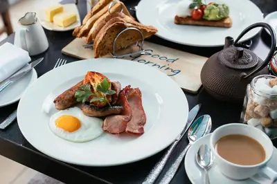 a table with plates of breakfast foods and a cup of coffee at Talland Bay Hotel, Looe in Talland