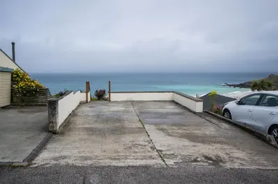 a car parked in a parking lot next to the ocean at Atlantic Heights Guest House in St Ives
