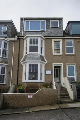 a large brick house with white windows and stairs at Atlantic Heights Guest House in St Ives