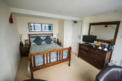 a bedroom with a bed and a mirror and a television at Atlantic Heights Guest House in St Ives