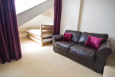 a living room with a leather couch with purple pillows at Atlantic Heights Guest House in St Ives