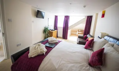a bedroom with a large white bed with purple pillows at Atlantic Heights Guest House in St Ives