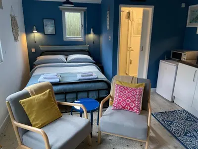a small room with a bed and two chairs at Fistral Studio in Newquay