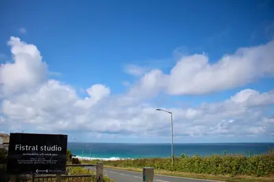 a sign on the side of a road near the ocean at Fistral Studio in Newquay