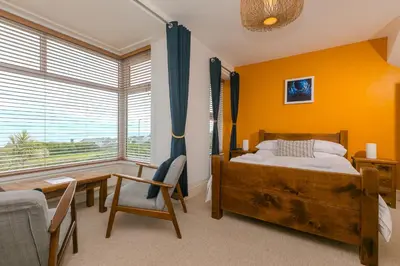 a bedroom with a bed and a desk and a window at Oystercatcher in St Ives