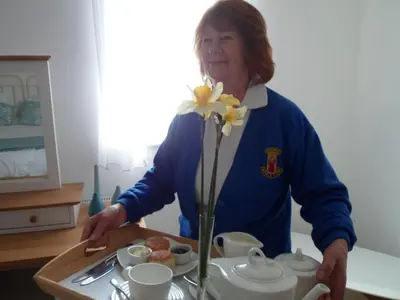 a woman standing in a kitchen with a tray of food at Padstow Bed & Breakfast in Padstow