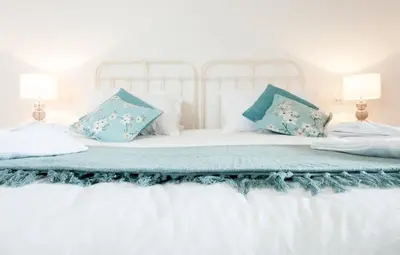 a white bed with blue pillows on it at Padstow Bed & Breakfast in Padstow