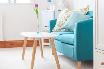 a living room with a blue couch and a white table at Padstow Bed & Breakfast in Padstow