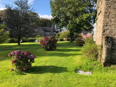 a yard with flowers in the grass next to a building at Almond Tree Cottage in Lanteglos