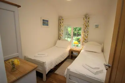 a small room with two beds and a window at Almond Tree Cottage in Lanteglos
