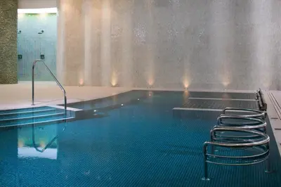 a swimming pool with a row of stools in it at The Headland Hotel and Spa in Newquay