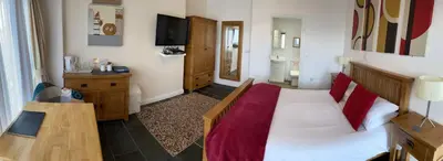 a room with a bed and a table and a television at Sawyers Bed and Breakfast in Looe