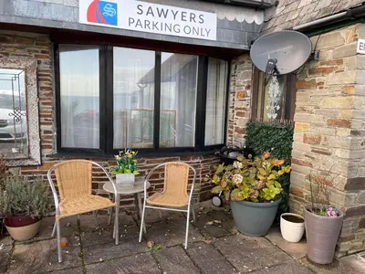 a patio with two chairs and a table in front of a building at Sawyers Bed and Breakfast in Looe