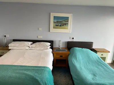 a bedroom with two beds and a nightstand with a bed sidx sidx sidx sidx at Sawyers Bed and Breakfast in Looe