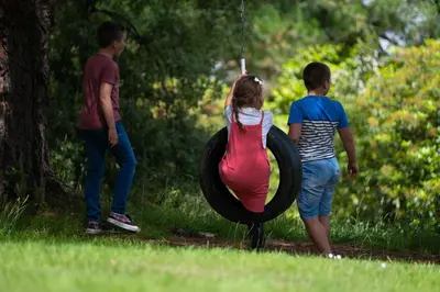 two boys and a girl playing with a tire swing at Fowey Hall Hotel in Fowey
