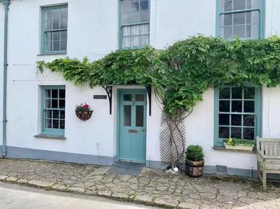 a white house with a blue door and a bench at Sea Haze Charlestown in St Austell