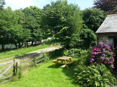 a wooden picnic table in the grass next to flowers at Sunflowers Barn in Looe