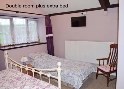 a bedroom with a bed and a chair at Sunflowers Barn in Looe