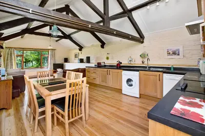a kitchen with a table and a sink and a dishwasher at Sunflowers Barn in Looe