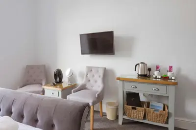 a living room with two chairs and a tv on a wall at Sure Hotel Collection by Best Western Porth Veor Manor Hotel in Newquay