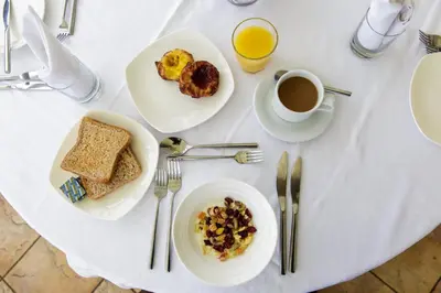 a white table with plates of food and a cup of coffee at Sure Hotel Collection by Best Western Porth Veor Manor Hotel in Newquay