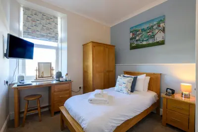 a bedroom with a bed and a desk and a television at Sure Hotel Collection by Best Western Porth Veor Manor Hotel in Newquay