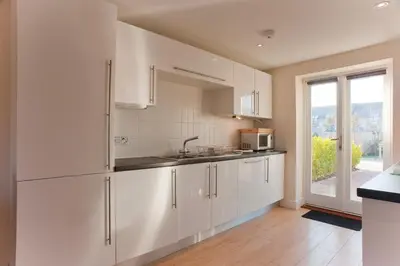 a white kitchen with a sink and a window at Bay Retreat Villas in Padstow