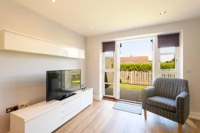 a living room with a flat screen tv and a chair at Bay Retreat Villas in Padstow