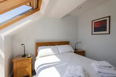 a bedroom with a bed with white sheets and a window at Bay Retreat Villas in Padstow