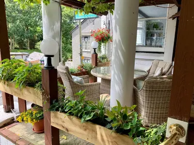 a patio with wicker chairs and tables and plants at The Claremont Hotel-Adult Only in Polperro