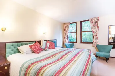 a bedroom with a large bed and two blue chairs at Penmorvah Manor Hotel in Falmouth