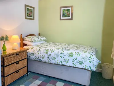 a bedroom with a bed and a dresser with a lamp at Spinnakers in Falmouth