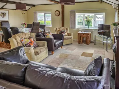 a living room with leather furniture and a tv at Driftwood in St Merryn