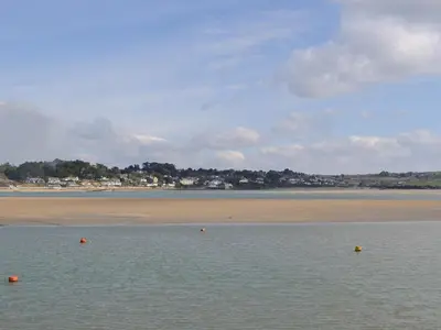 a body of water with a beach in the background at Driftwood in St Merryn
