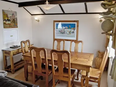 a dining room with a wooden table and chairs at Driftwood in St Merryn