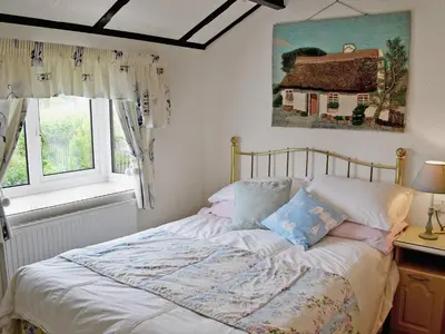 a bed in a bedroom with a picture of a house at Driftwood in St Merryn