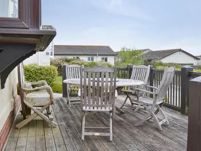 three chairs and a table on a deck at Driftwood in St Merryn