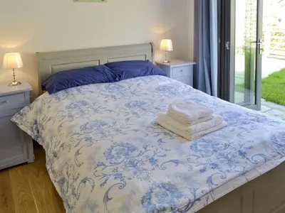 a bed with a blue and white comforter with towels on it at Kataluma in Germoe