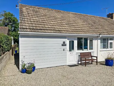 a white garage with a bench in front of it at Puffins in Port Isaac