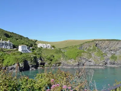 a group of houses on a cliff next to a body of water at Puffins in Port Isaac