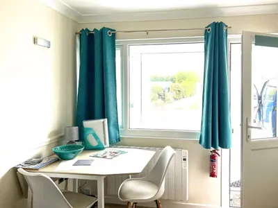 a room with a table and chairs and a window at Puffins in Port Isaac